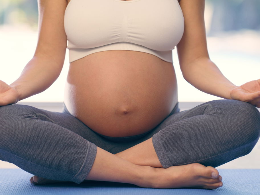 Nahaufnahme von schwangerer Frau beim Yoga.