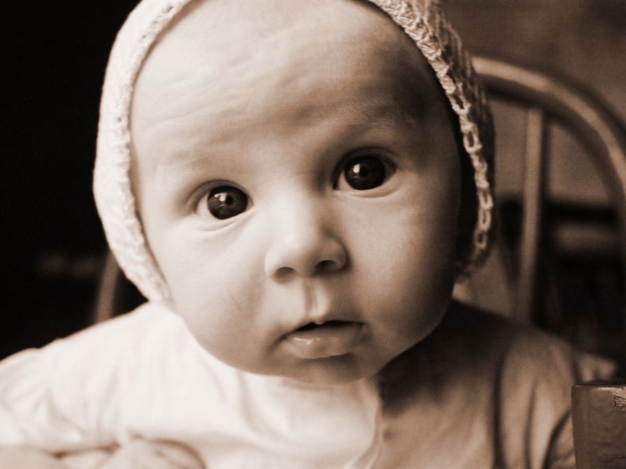Schwarzweiß-Foto von Baby mit Mützchen.
