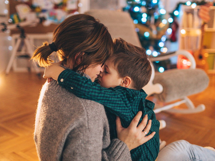 Kleiner Junge kuschelt mit seiner Mama, nachdem sie seine Weihnachtswünsche gelesen hat.