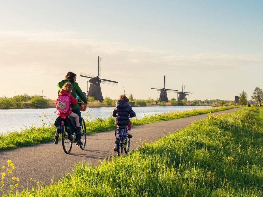 Holländische Familie fährt Fahrrad entlang von niederländischen Windmühlen.