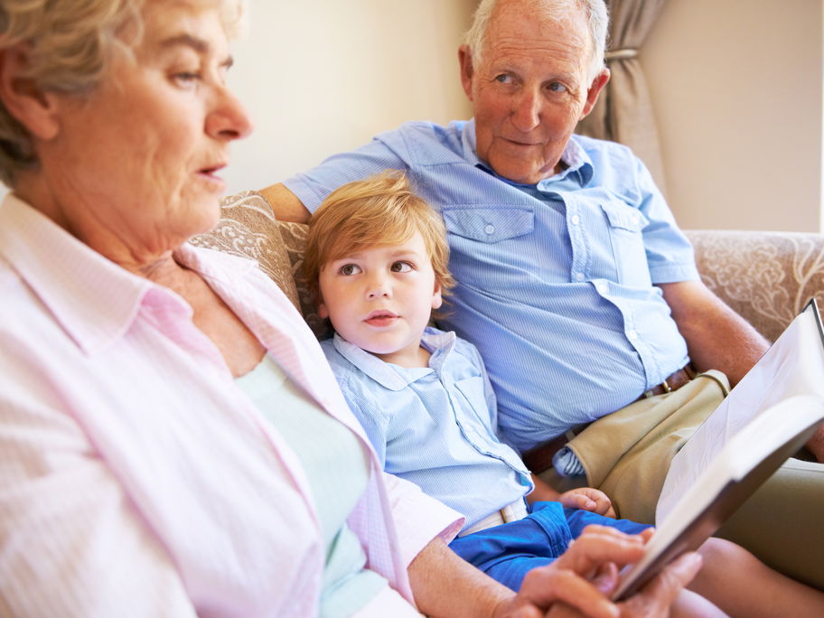 Oma und Opa lesen mit dem Enkel ein Buch.