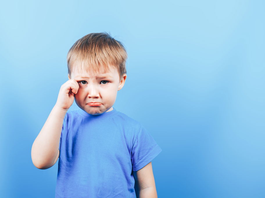 Kleiner Junge mit Schmollmund, reibt sich das Auge.