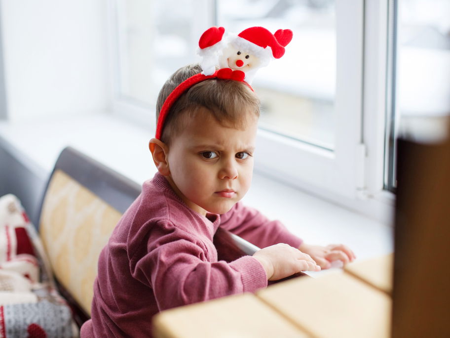 Ein Kind mit Weihnachtsmannhaarreif, der sauer gut