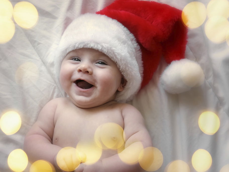 Lachendes Baby mit Weihnachtsmütze.
