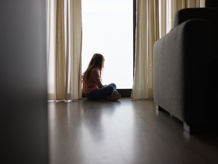 Ein Kind sitzt allein am Fenster