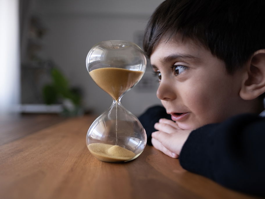 Kleiner Junge schaut auf die Sanduhr: Mama hat einen Timer gestellt.