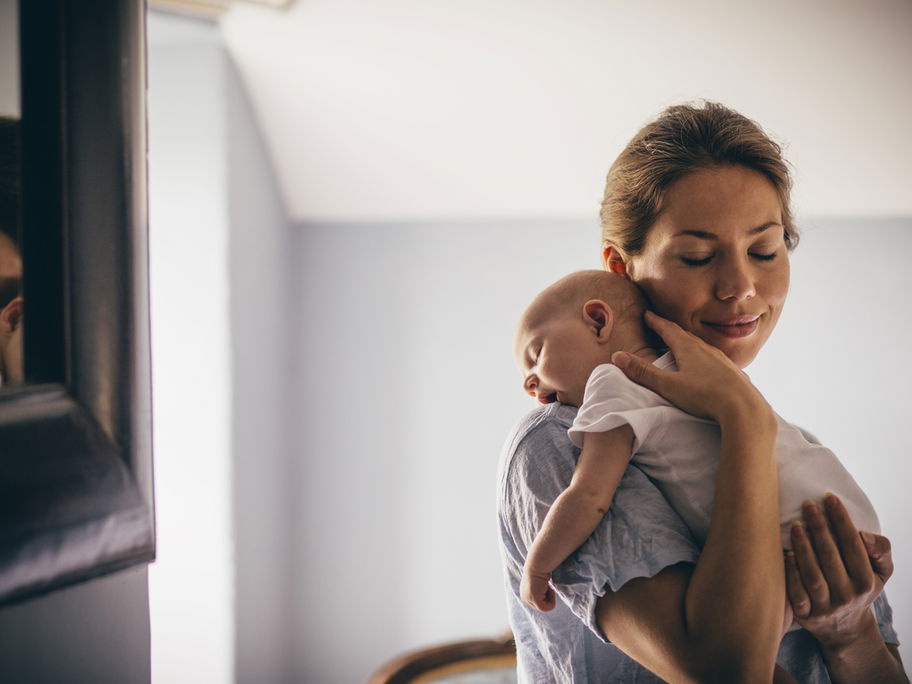 Mama trägt ihr Baby liebevoll im Arm.