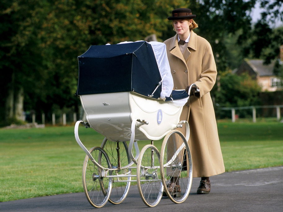 Eine Norland-Nanny schiebt ein Baby im Kinderwagen draußen durch die Gegend.