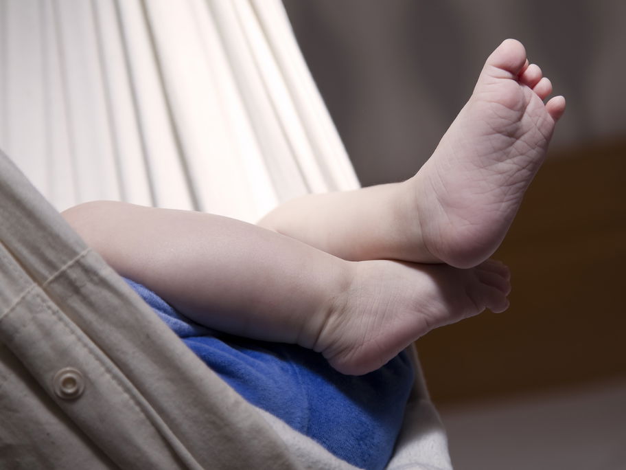 Babyfuß ragt aus der Federwiege.