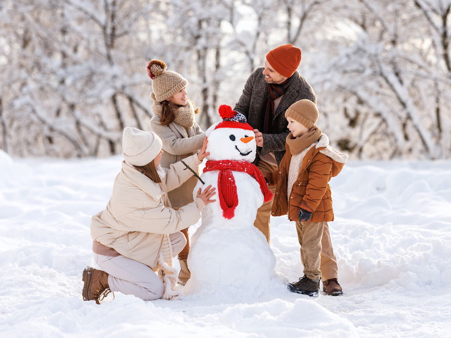 Eine vierköpfige Familie baut einen Schneemann.