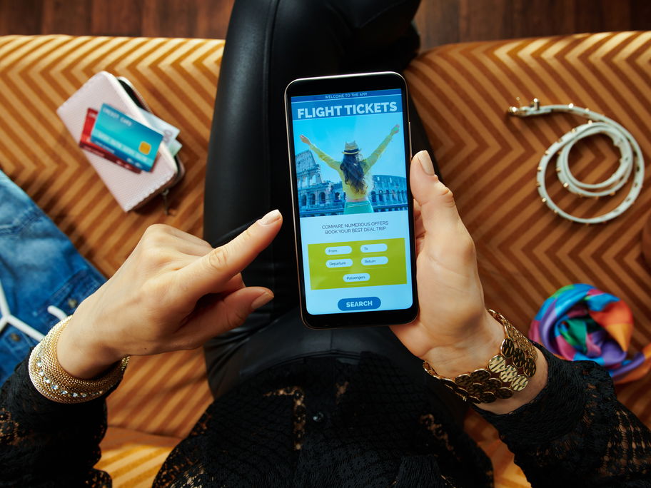 Frau bucht über ihr Handy eine Reise.