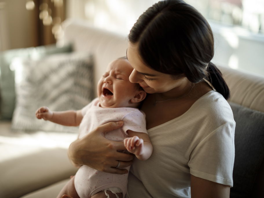 Mama hält zitterndes Baby im Arm.