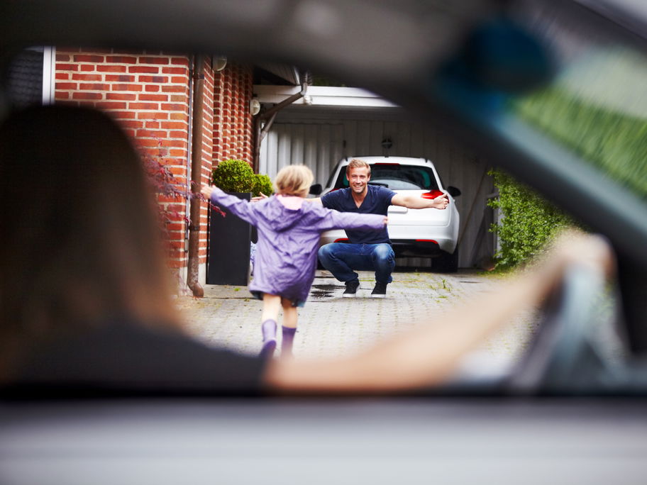 Kind läuft vom Auto der Mama zum Papa.