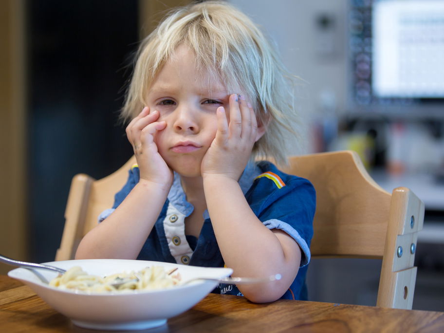 Kleiner, blonder Junge ist enttäuscht von seinem Essen.