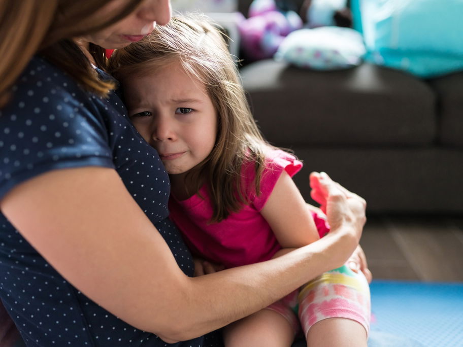 Mutter tröstet ihre kleine Tochter und hält sie im Arm.
