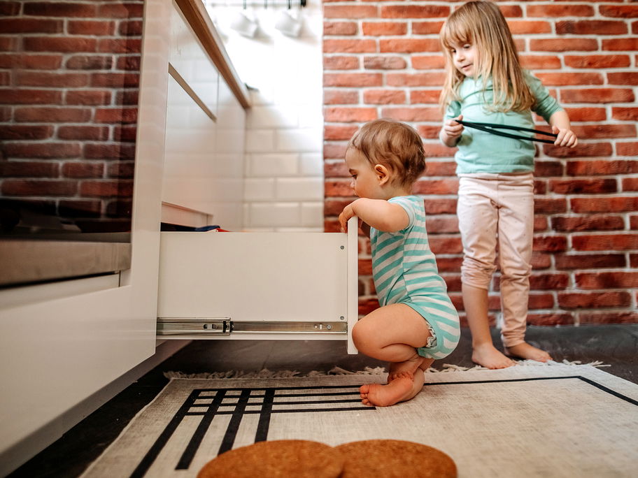 Zwei kleine Kinder schauen nach Süßigkeiten in der Ja-Schublade.
