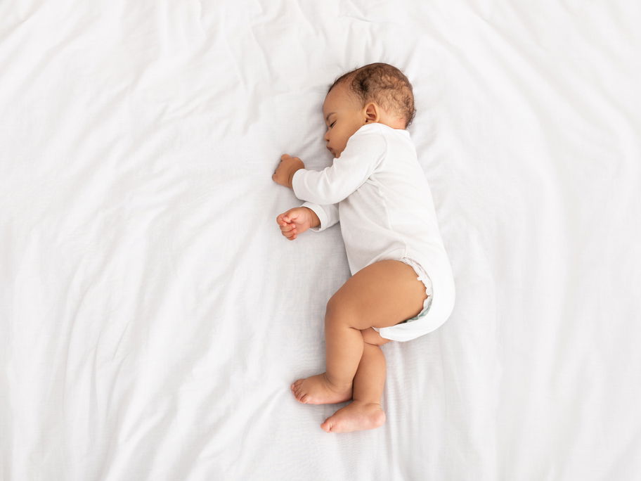 Baby liegt schlafend auf der Seite im Bett