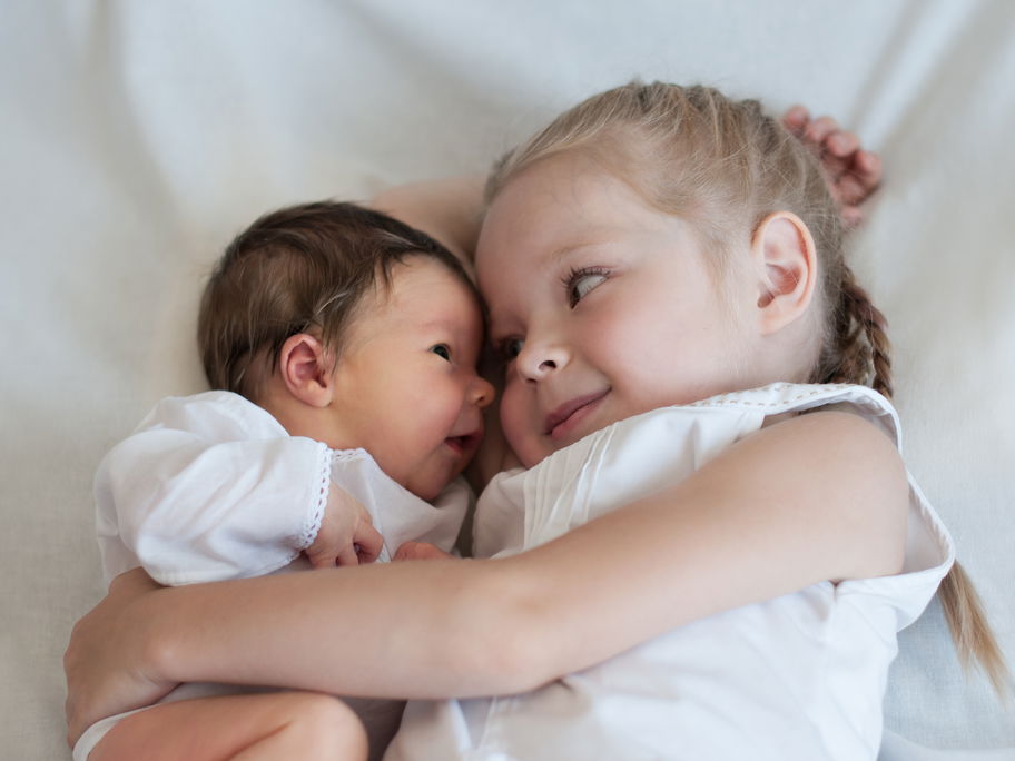 Mädchen hält Baby im Arm.