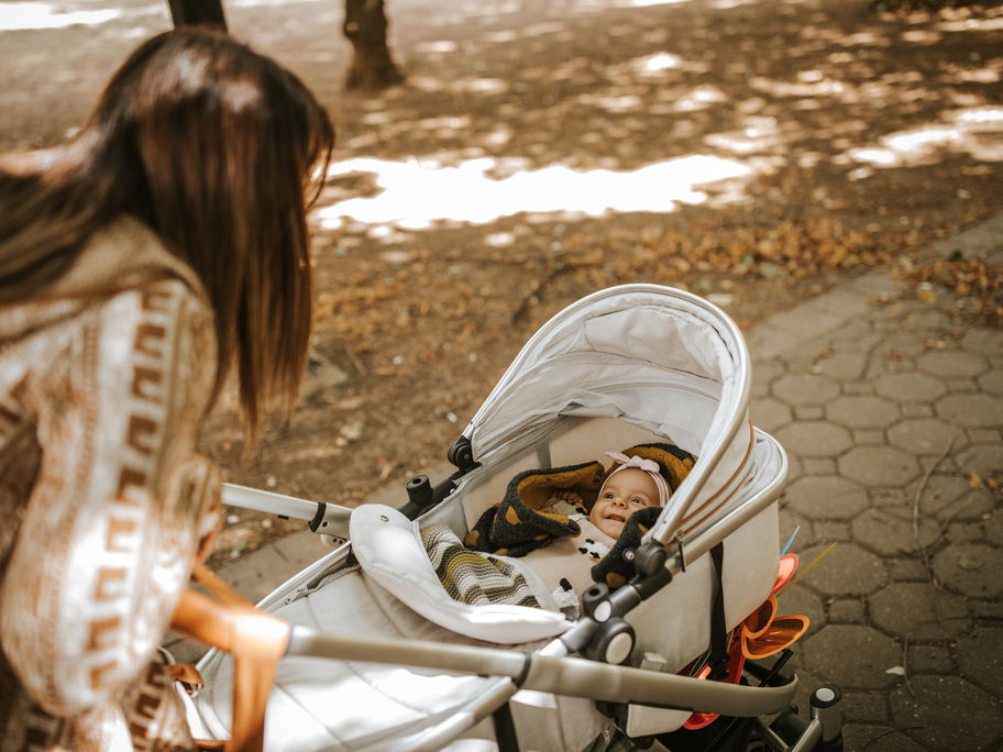 Mutter schiebt Baby im Kinderwagen.