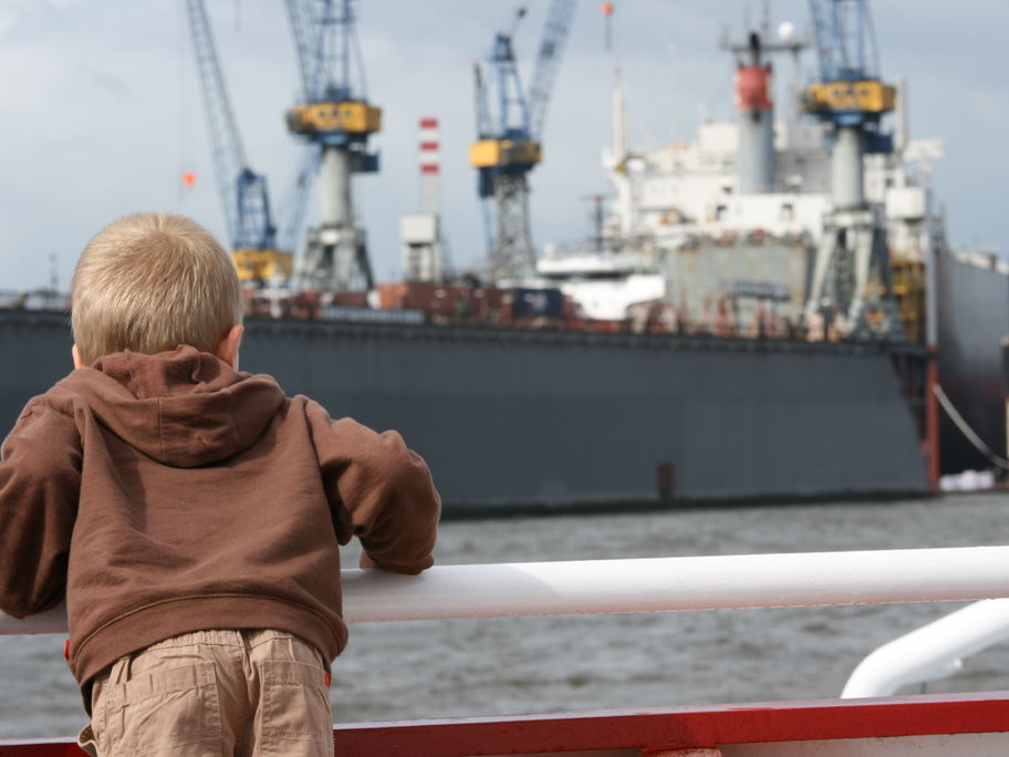 Junge bestaunt Schiff am Hamburger Hafen.