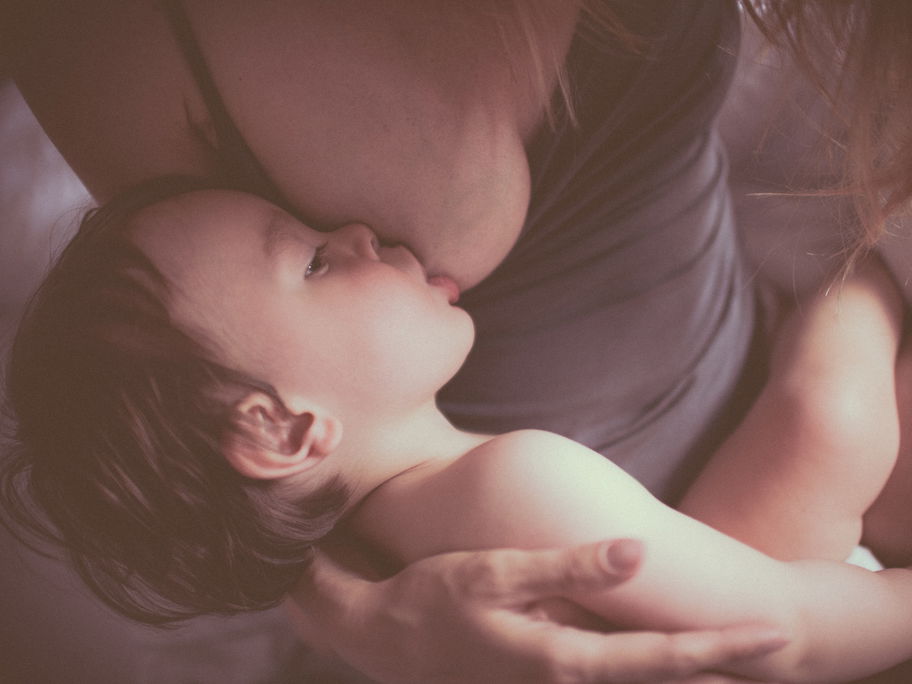 Ein kleines Kind, das von seiner Mutter gestillt wird.