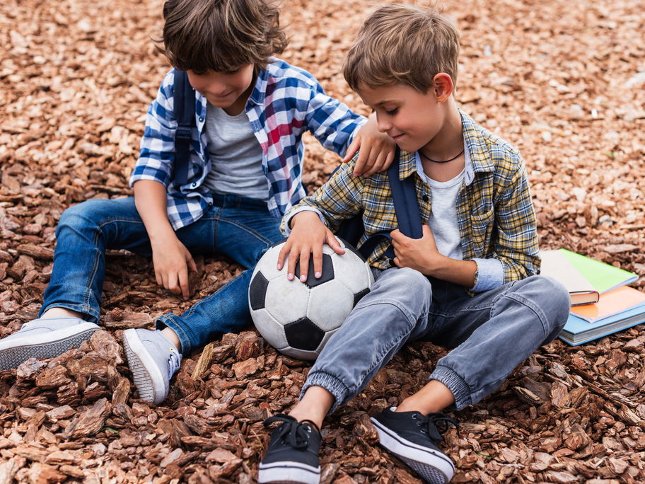 Zwei Jungen mit Fußball und Büchern.