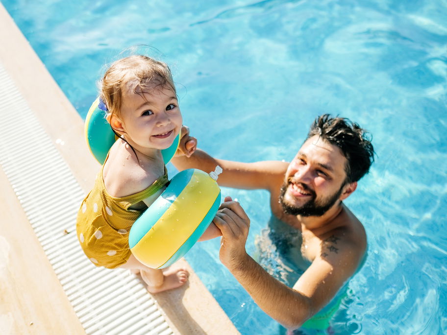 Kleinkind mit Schwimmflügeln und Papa.