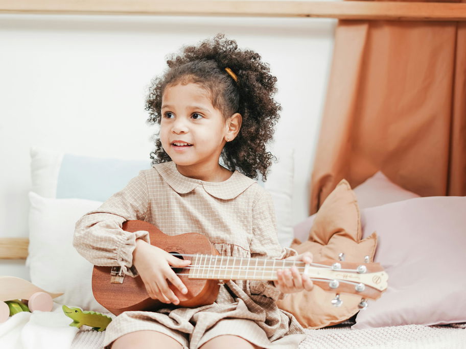Kleines Mädchen spielt Ukulele.