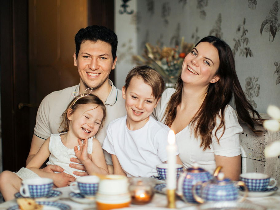 Eine glückliche, vierköpfige Familie ist abgebildet.
