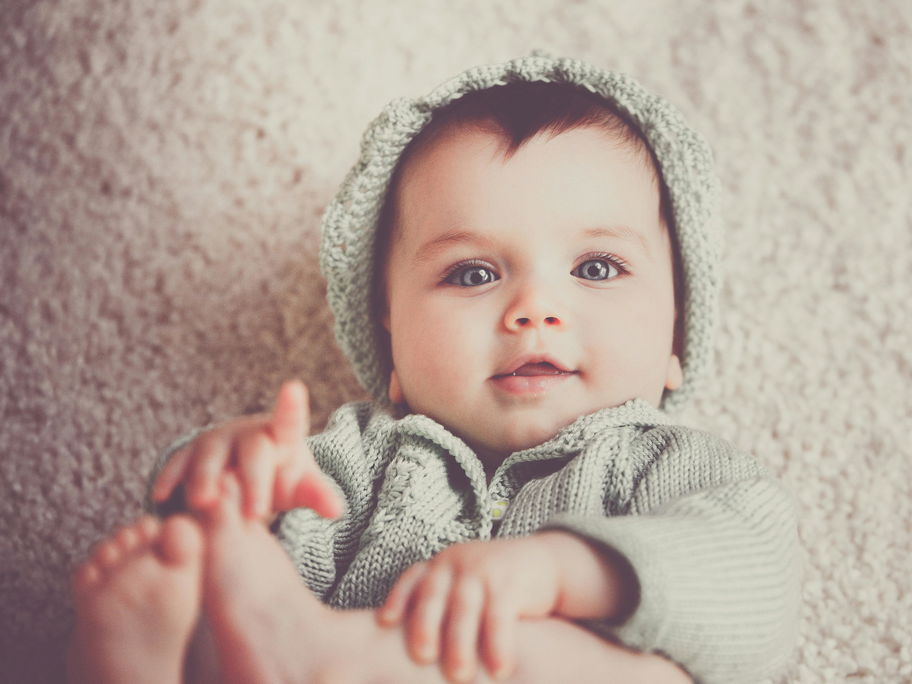 Baby liegt auf dem Rücken und schaut in die Kamera.