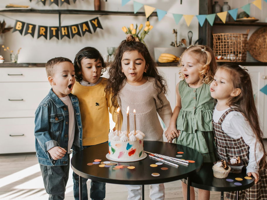 Drei kleine Mädchen und zwei kleine Jungs feiern Kindergeburtstag ohne Eltern.