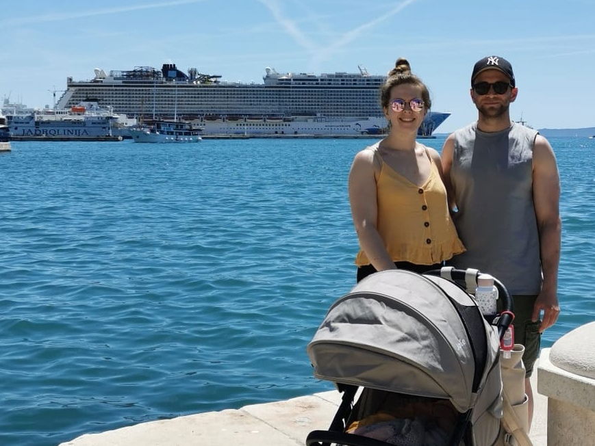 Unsere Autorin, ihr Mann und ihr Kind im Buggy stehen am Hafen in Split vor dem Kreuzfahrtschiff Norwegian Escape.