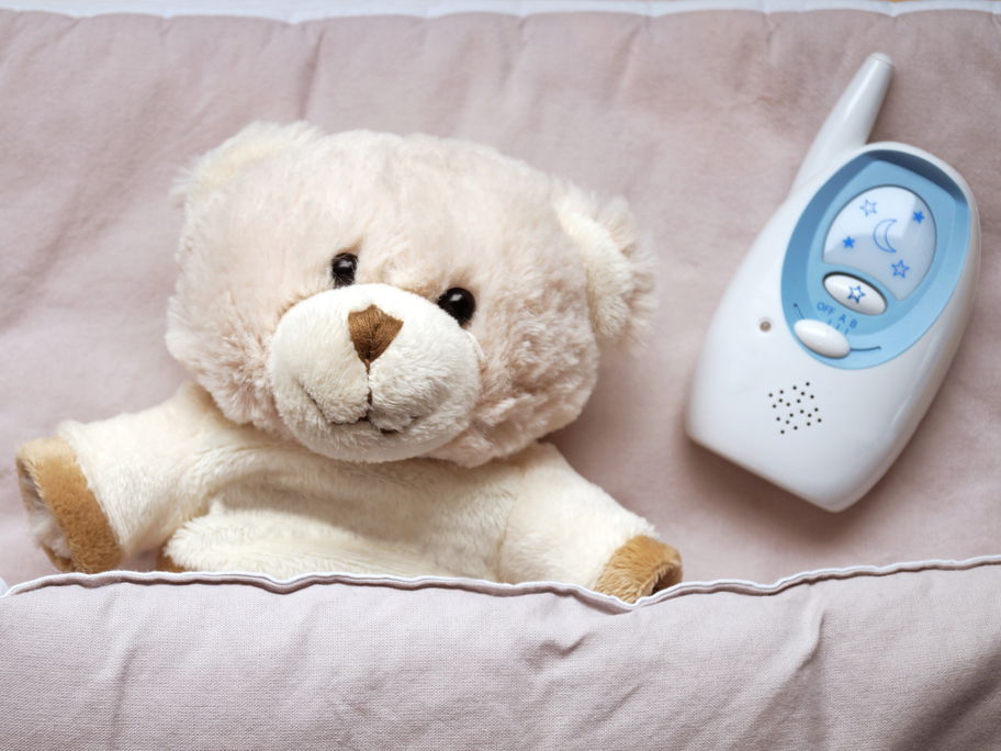 Ein Teddy liegt neben einem Babyphone.