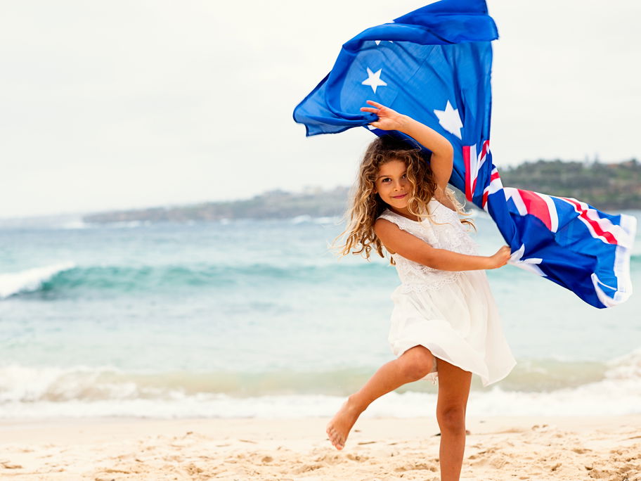 Ein Mädchen mit australischer Flagge am Strand.
