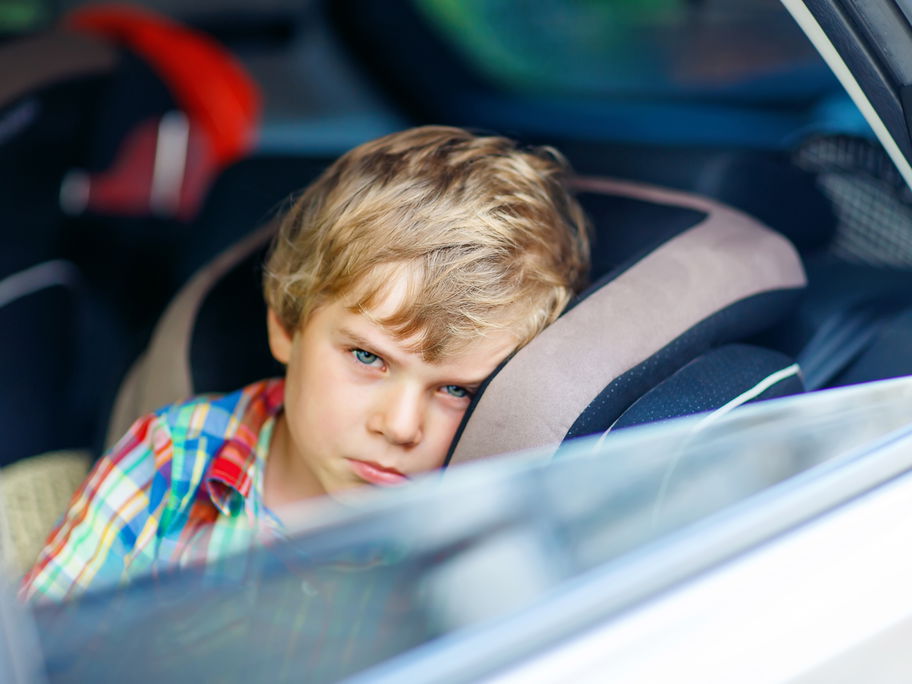 Ein kleiner Junge schaut aus dem offenen Autofenster.