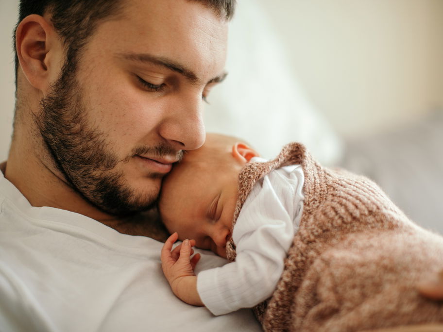 Kleines Baby schläft auf der Brust des Vaters.