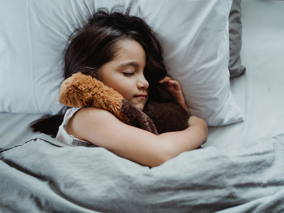 Ein Mädchen liegt schlafend in ihrem Bett.