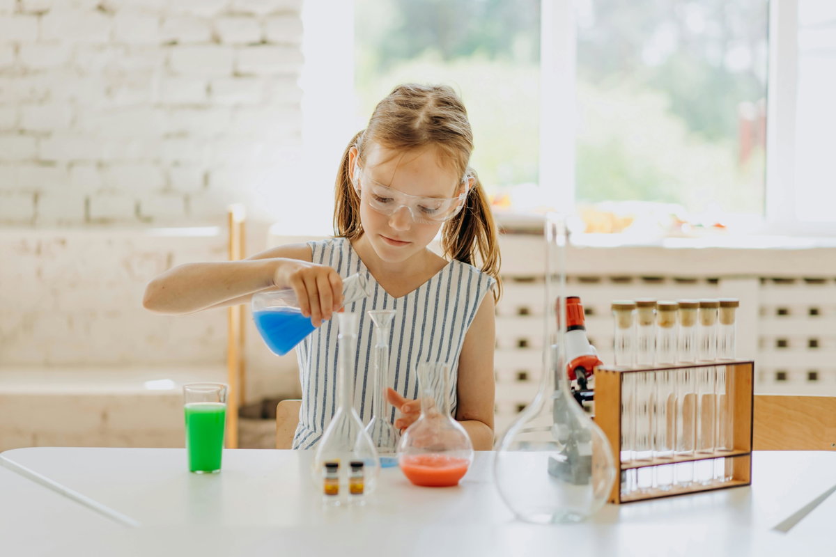 Mädchen experimentiert mit bunten Flüssigkeiten.