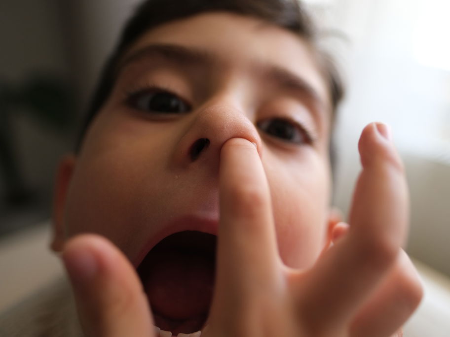 Ein kleiner Junge steckt seinen Finger in die Nase.