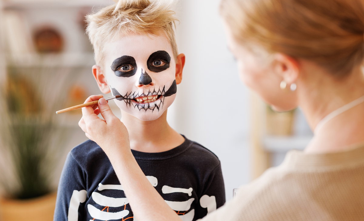 Mutter schminkt ihren Sohn als Skelett