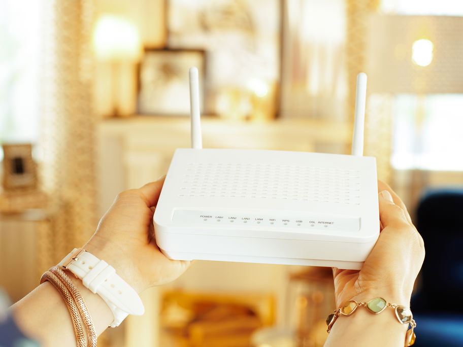 Frau hält einen WLAN-Router in der Hand.
