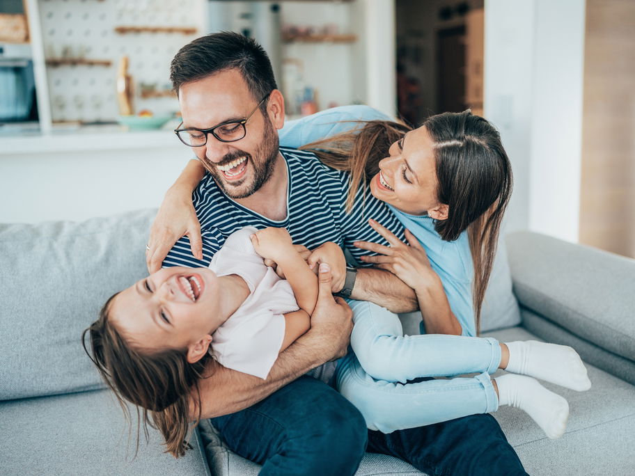 Fröhliche Familie tobt auf dem Sofa.