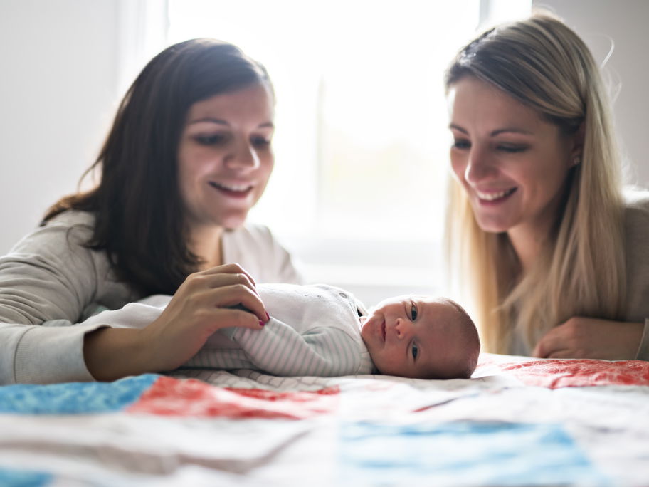 Zwei Frauen lächeln ein Baby an.