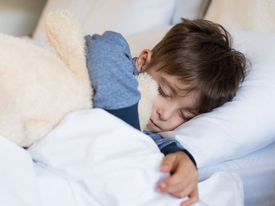 Junge liegt im Bett und schläft.