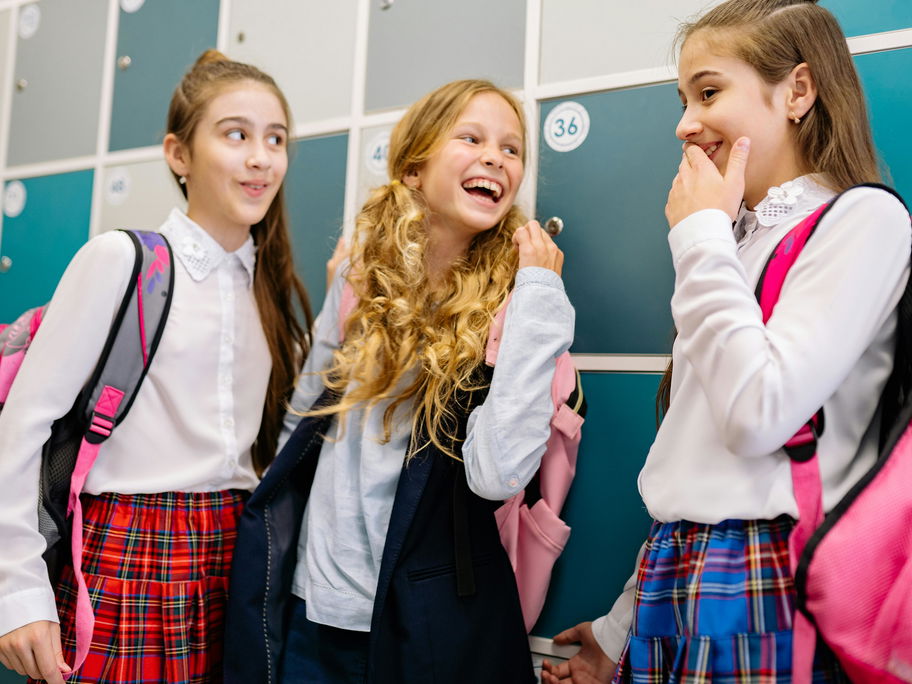 Drei Mädchen erzählen sich in der Schule einen Witz.