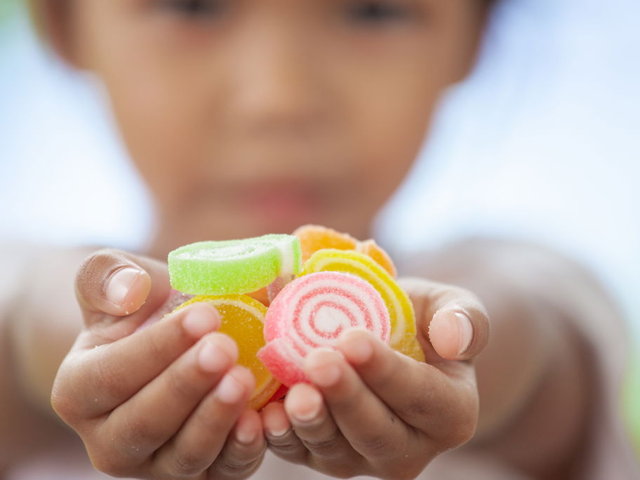 Kind hält Fruchtgummis in der Hand.