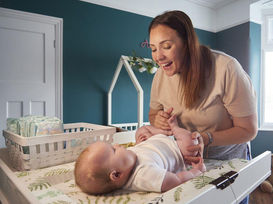 Eine Mutter wechselt ihrem Baby auf einer Wickelkommode die Windel.