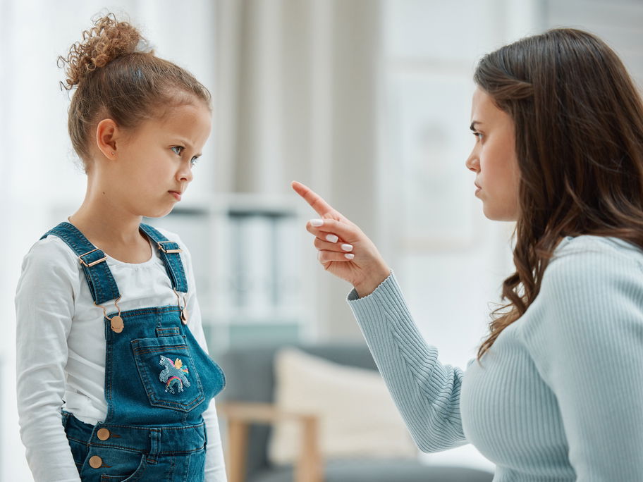 Mutter schimpft mit erhobenem Zeigefinder mit ihrer Tochter.