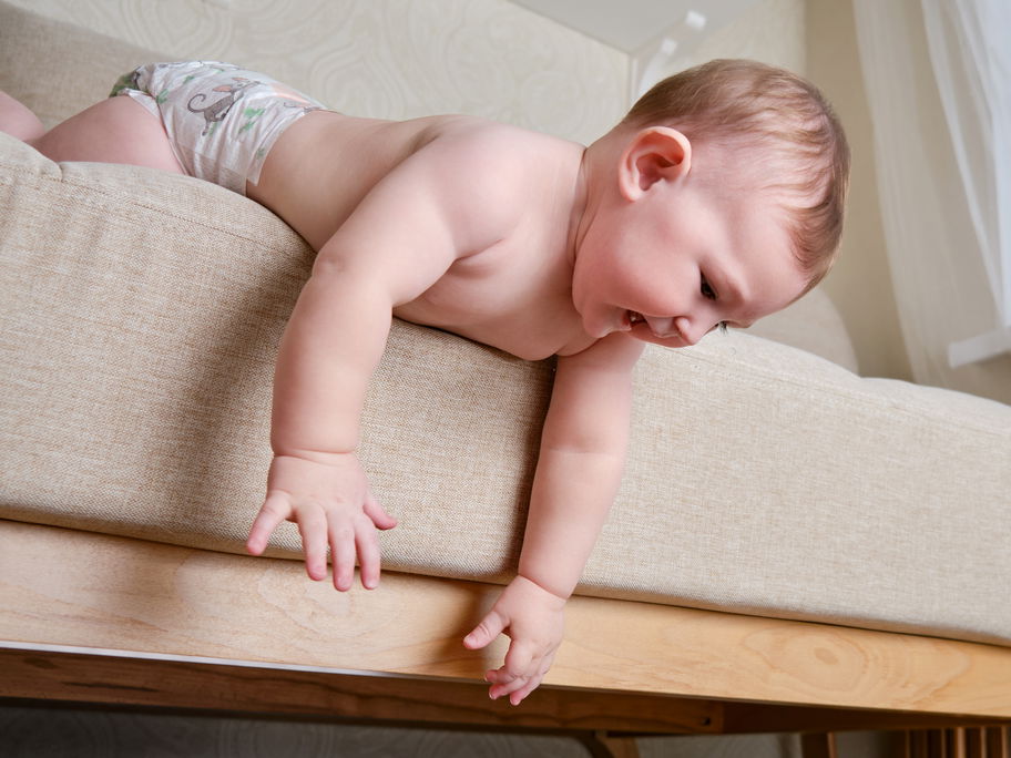 Baby beugt sich über den Bettrand.