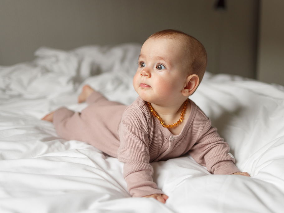 Ein Baby trägt eine Bernsteinkette um den Hals.